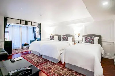 two beds in a white room with a desk at Akara Hotel in Bangkok