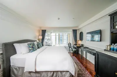 a bedroom with a large white bed and a desk at Akara Hotel in Bangkok