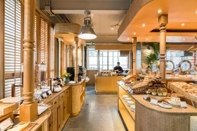 a bakery with wooden counters and a man in the background at Akara Hotel in Bangkok