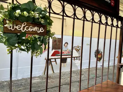 a woman sitting in a chair behind a gate at KC guest house in Bangkok