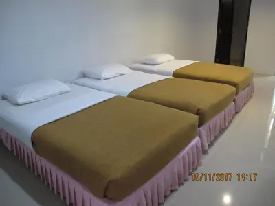 three beds are lined up in a room at Tongpoon Hotel in Bangkok