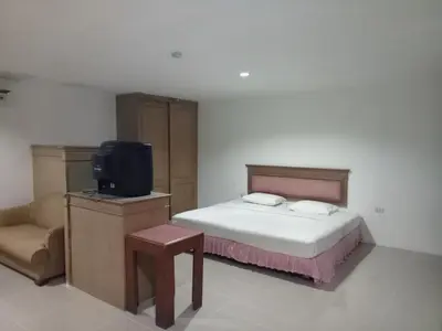 a bedroom with a bed and a tv and a chair at Tongpoon Hotel in Bangkok