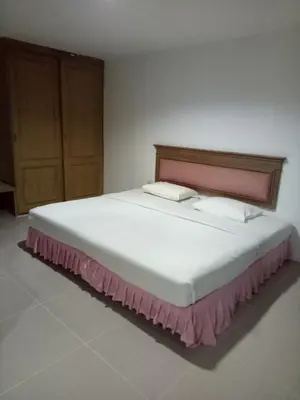 a bedroom with a large white bed with a wooden headboard at Tongpoon Hotel in Bangkok
