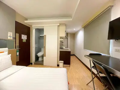 a room with a bed and a desk and a bathroom at Arawana Express Phromphong in Bangkok