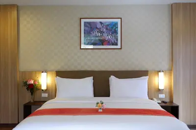 a bedroom with a large bed with white sheets at Dynasty Inn in Bangkok