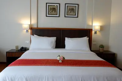 a bedroom with a large white bed with two pillows at Dynasty Inn in Bangkok