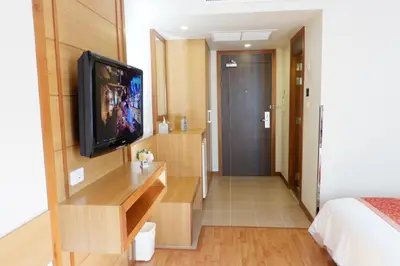 a hotel room with a television and a bedroom at Dynasty Inn in Bangkok