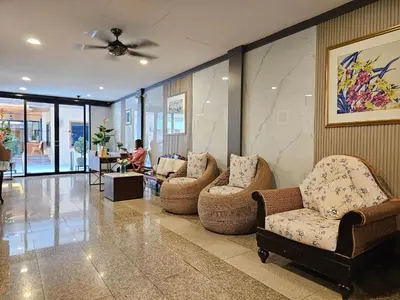 a lobby with chairs and a table and a person in the background at Dynasty Inn in Bangkok