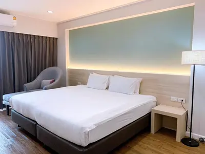 a hotel room with a large bed and a chair at Miloft Sathorn Hotel in Bangkok
