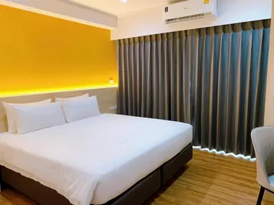 a bedroom with a large bed and a yellow wall at Miloft Sathorn Hotel in Bangkok