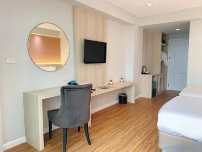 a hotel room with a desk and a bed and a mirror at Miloft Sathorn Hotel in Bangkok