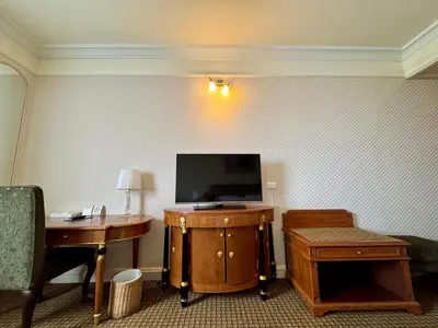 a hotel room with a tv and a table and a desk at Royal Benja Hotel - Big Rooms, Family Friendly in Bangkok