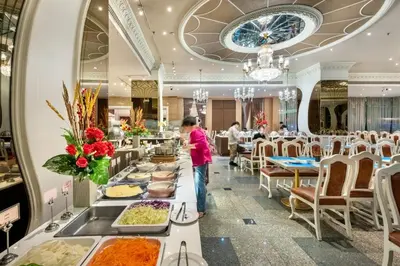 a woman standing in front of a buffet line of food at Royal Benja Hotel - Big Rooms, Family Friendly in Bangkok