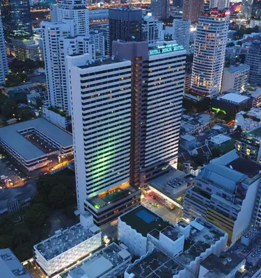 an aerial view of a tall building in a city at night at Royal Benja Hotel - Big Rooms, Family Friendly in Bangkok