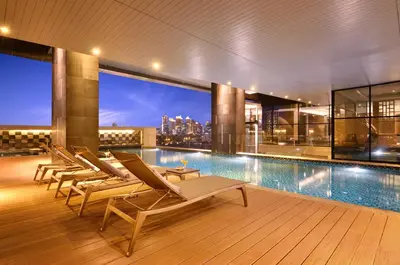 a pool on the roof of a building with lounge chairs at AETAS lumpini in Bangkok