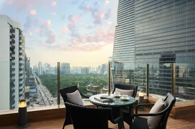 a balcony with a table and chairs and a view of a city at AETAS lumpini in Bangkok
