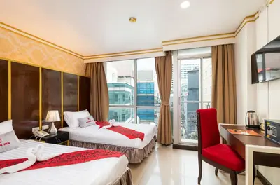 a hotel room with two beds and a red chair at Khurana Inn in Bangkok