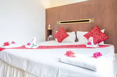 a bedroom with a large white bed with red pillows at Khurana Inn in Bangkok