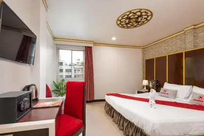 a hotel room with a large bed and a red chair at Khurana Inn in Bangkok