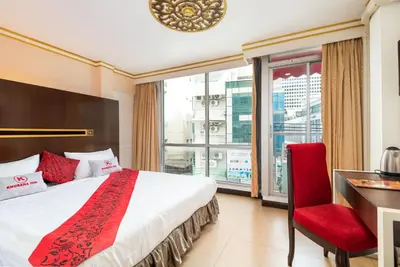 a hotel room with a bed and a desk and a window at Khurana Inn in Bangkok