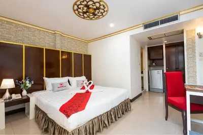a bedroom with a large bed and a red chair at Khurana Inn in Bangkok