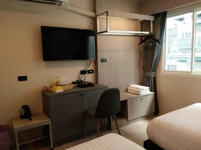 a hotel room with a desk and a tv on the wall at Lazy Sunday hostel in Bangkok
