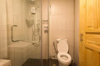 a bathroom with a toilet and a glass shower at Lazy Sunday hostel in Bangkok