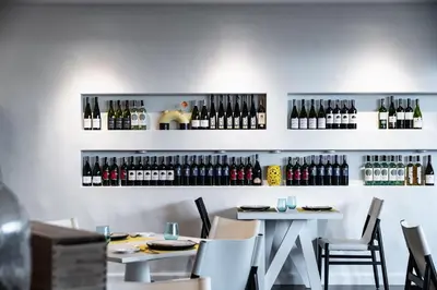 a restaurant with two tables and wine bottles on the wall at MUU Bangkok, Small Luxury Hotels of the World in Bangkok