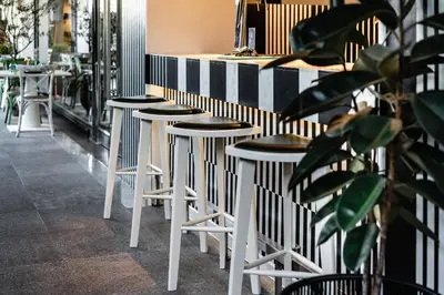 a row of stools in front of a bar at MUU Bangkok, Small Luxury Hotels of the World in Bangkok