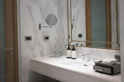 a white bathroom with a sink and a mirror at MUU Bangkok, Small Luxury Hotels of the World in Bangkok