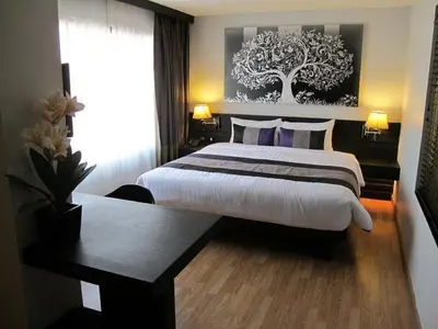 a hotel room with a large bed and a window at Nouvo City Hotel in Bangkok