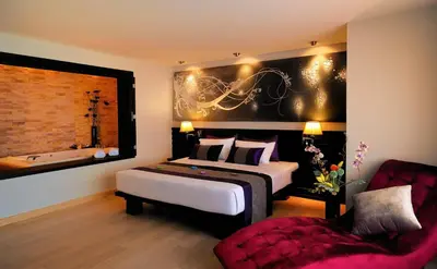 a bedroom with a bed and a couch and a chair at Nouvo City Hotel in Bangkok