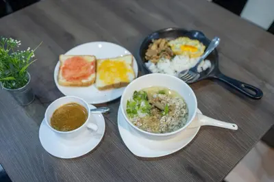 a table with two plates of food and two cups of coffee at Baansuay Rattanathibet Apartment in Nonthaburi