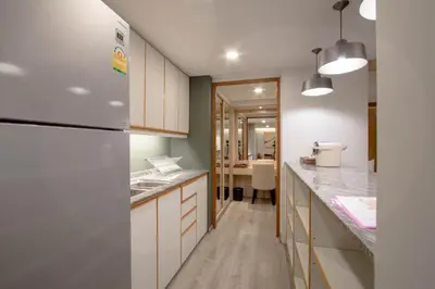 a kitchen with white cabinets and a refrigerator at The Residence Rajtaevee Hotel in Bangkok