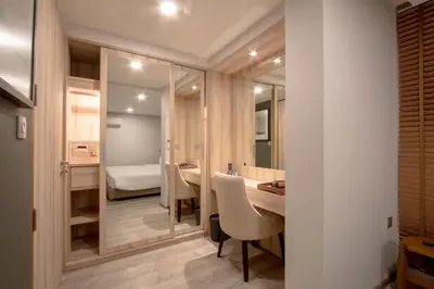 a bathroom with a sink and a mirror and a bedroom at The Residence Rajtaevee Hotel in Bangkok