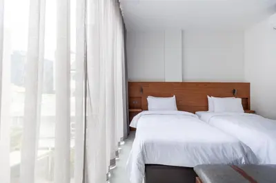 two beds in a room with a large window at Reno hotel in Bangkok
