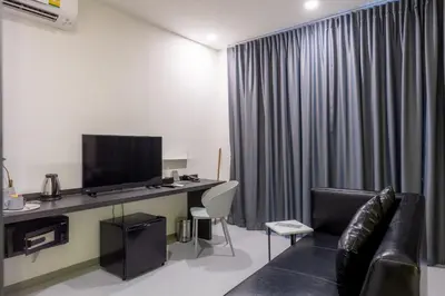a room with a couch and a desk with a television at Reno hotel in Bangkok
