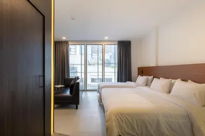 a hotel room with two beds and a chair at Reno hotel in Bangkok