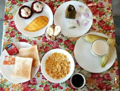 a table with plates of breakfast food on a floral table cloth at Home & Hashery Boutique House in Bangkok
