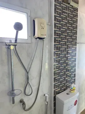 a shower in a bathroom next to a toilet at Kurina Hotel in Bangkok