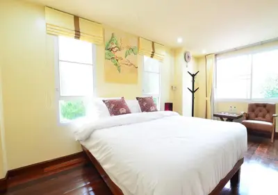 a bedroom with a large white bed and two windows at Ayi Home in Bangkok