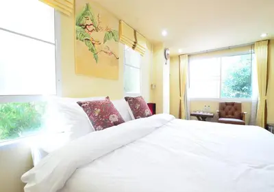 a bedroom with a white bed and a window at Ayi Home in Bangkok