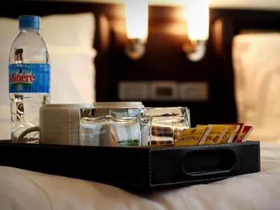 a tray with a bottle of water and glasses on a bed at Gulliver's Tavern Hotel in Bangkok