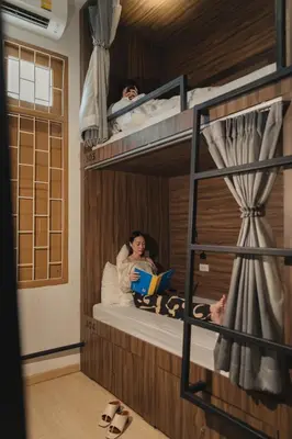 two people sitting in bunk beds with a book at Hostel Urby in Bangkok