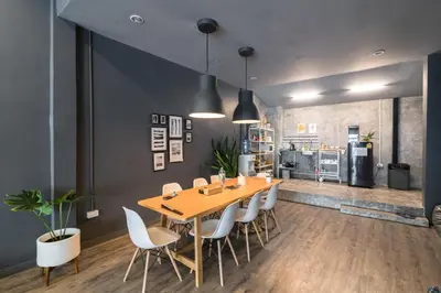 a dining room with a wooden table and white chairs at The Cocoon Hostel in Bangkok