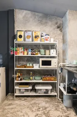 a kitchen with a shelf with food on it at The Cocoon Hostel in Bangkok