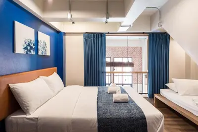 a bedroom with a large bed with blue walls at Natee Hostel in Bangkok