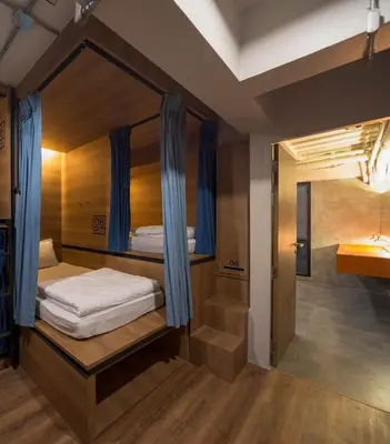 a room with a bunk bed with blue curtains at Natee Hostel in Bangkok