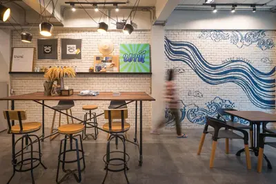 a person walking in a room with tables and stools at Natee Hostel in Bangkok