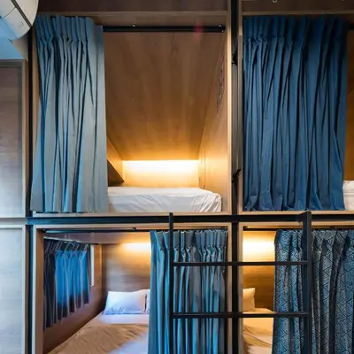 two bunk beds in a room with blue curtains at Natee Hostel in Bangkok